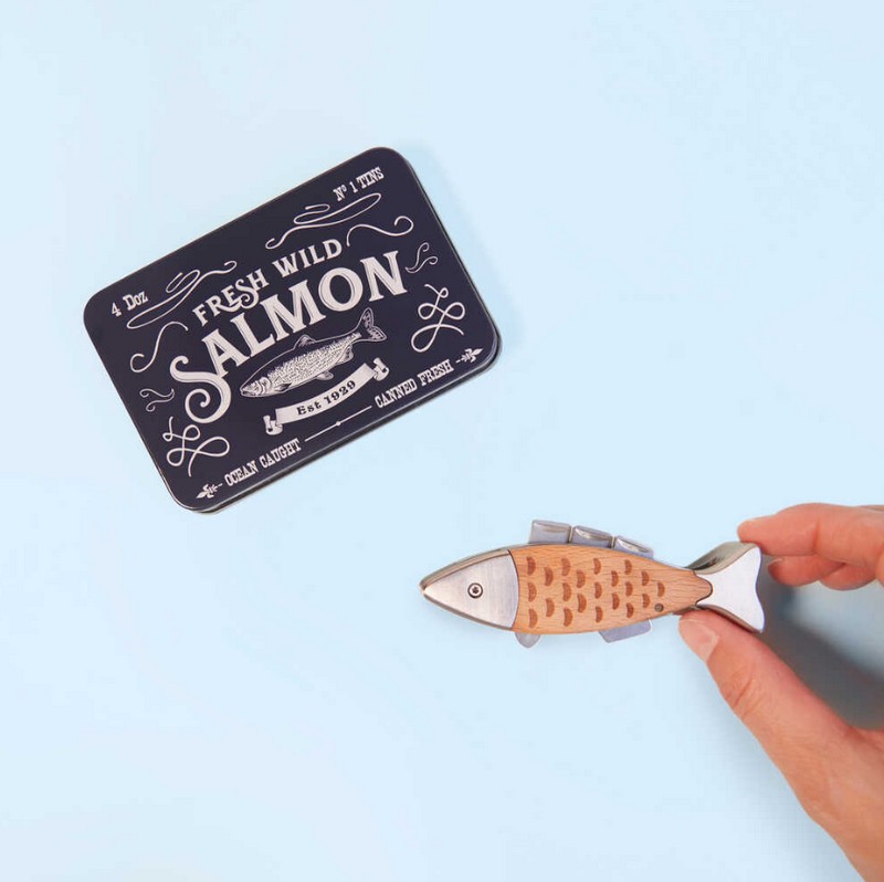 Coltellino multiuso a forma di salmone con finiture in legno contenuto in una scatola di latta